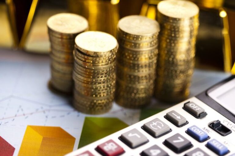 photo d'une calculatrice, de graphiques colorés et de pièces de monnaie pour illustrer les analyse des coûts proposées par la spécialiste achats et supply chain durables Katia Gutknecht